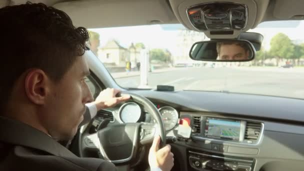 Особистий водій у чорному костюмі веде машину по міських вулицях — стокове відео