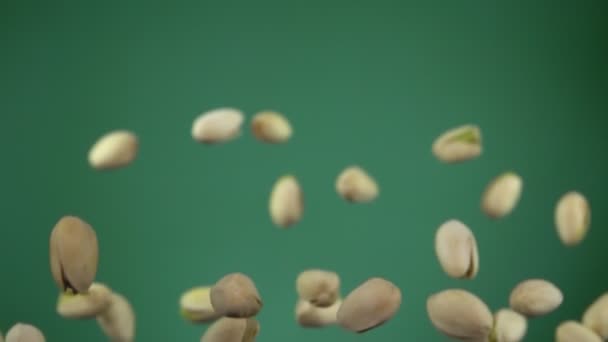 Los pistachos salados rebotan y giran sobre el fondo verde — Vídeos de Stock