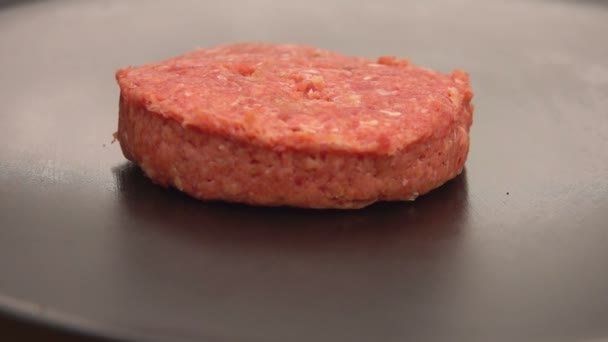 Raw cutlet for a burger is placed with on the flat grill surface — Stock Video