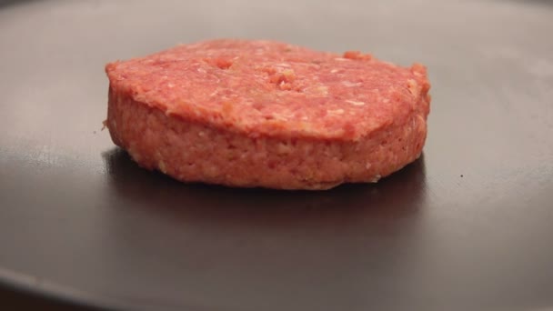 Côtelette crue pour un hamburger est placé avec sur la surface du gril plat — Video