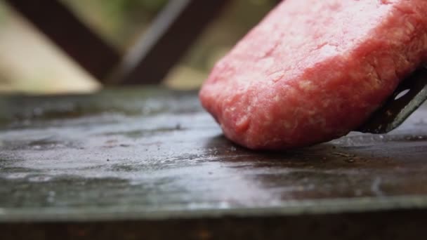 Rundvleessnijder voor een hamburger wordt buiten op de metalen grill geplaatst — Stockvideo