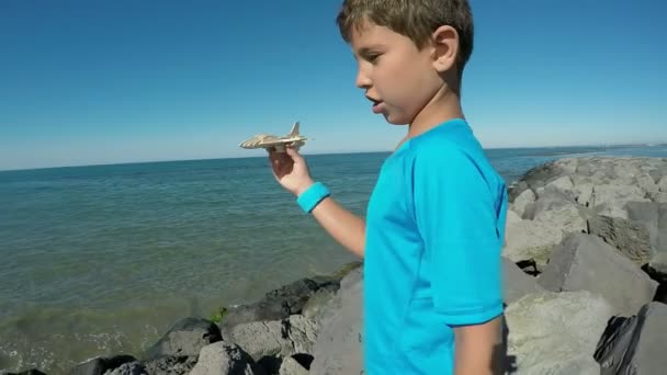 Un niño juega con un modelo de avión en un fondo del mar — Vídeos de Stock