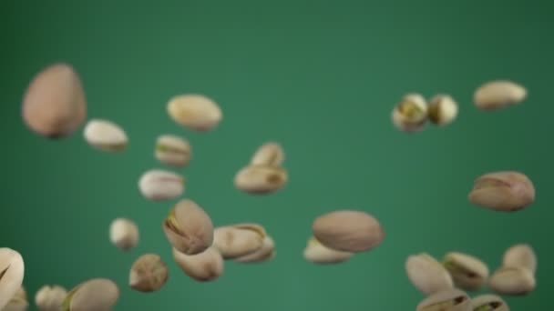 Los pistachos salados están volando y girando sobre el fondo verde — Vídeos de Stock