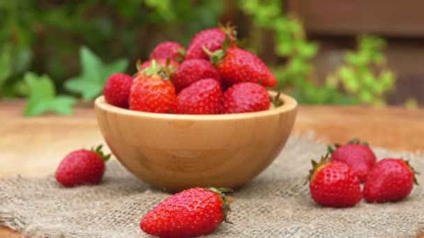 Un tazón de madera lleno de fresas rojas yacía en la mesa sobre la servilleta de arpillera — Vídeos de Stock