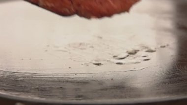 Hamburger için çiğ sığır pirzolası düz ızgara yüzeyine konur.