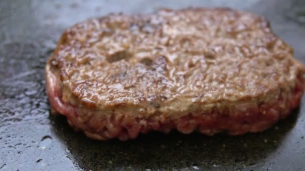 Primer plano de jugosa chuleta de ternera para una hamburguesa volteada en la parrilla de metal — Vídeos de Stock