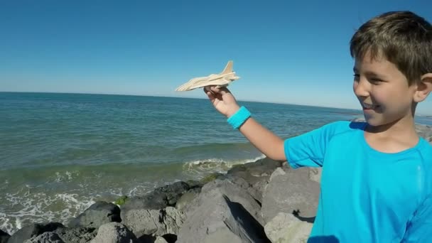 Um menino alegre está sorrindo e brincando com um modelo de avião — Vídeo de Stock