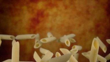 Çiğ makarna penne yukarı uçuyor ve sarı bir arkaplanın üzerine düşüyor.