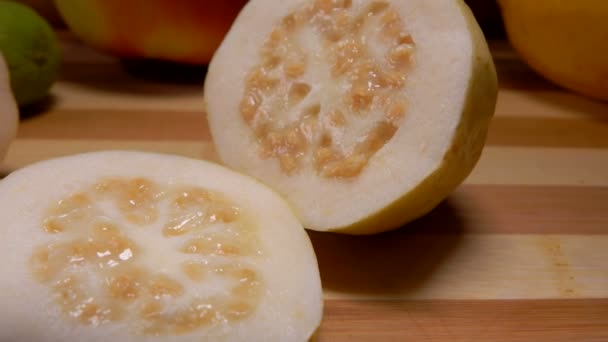 Panorama de deliciosas fatias redondas de goiaba exóticas deitadas em uma tábua de corte — Vídeo de Stock