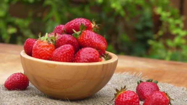 Hand prend une fraise rouge juteuse dans le bol en bois — Video