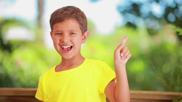 De vrolijke jongen in een geel t-shirt dreigt spottend met een vinger — Stockvideo