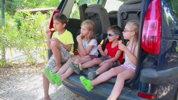 Vidám gyerekek színes ruhában finom jégkrémet esznek. — Stock videók