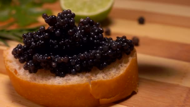 Primo piano di un cucchiaio premendo delizioso caviale nero alla fetta di pane — Video Stock