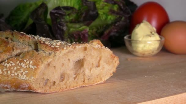 Baguette de cereal francés recién horneado con semillas de sésamo cortadas con un cuchillo — Vídeo de stock