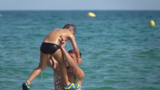 Mladý muž hodí chlapce do vody s cákáním — Stock video