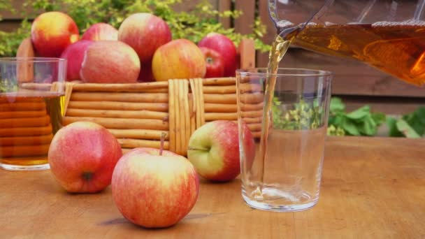 Leckerer frischer Apfelsaft wird aus dem Krug ins Glas geschüttet — Stockvideo