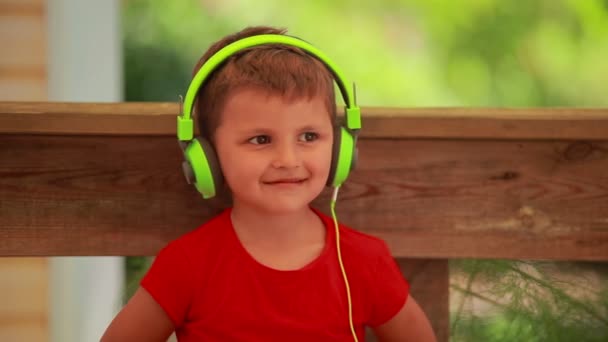 Le petit garçon dans le casque écoute de la musique sur la tablette numérique — Video