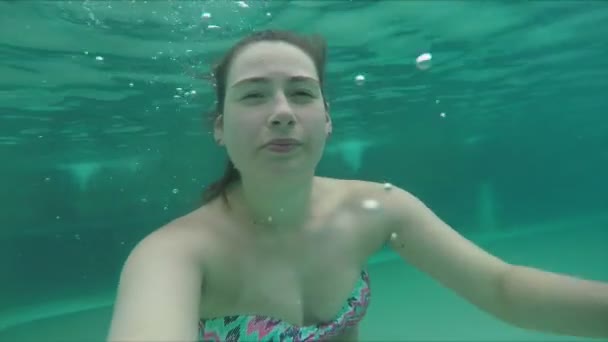 En ung kvinna i baddräkt dyker och simmar under vattnet. — Stockvideo
