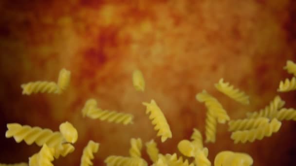 Rauwe droge pasta fusili vliegt omhoog en valt neer op een gele oker achtergrond — Stockvideo
