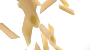 Beyaz arka planda çapraz uçan kuru, çiğ makarna makarnasından yakın çekim.