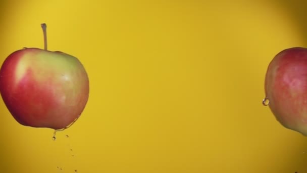 Two large ripe red apples are colliding on the yellow background — Stock Video