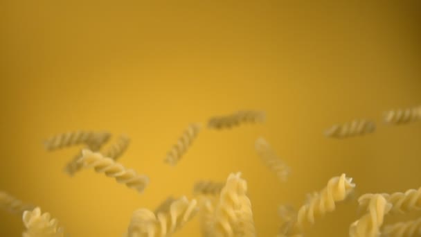 Suchy makaron fusilli latający w górę i obracający się na żółtym tle — Wideo stockowe