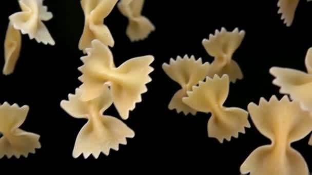 Torr pasta Farfalle faller diagonalt på en svart bakgrund — Stockvideo