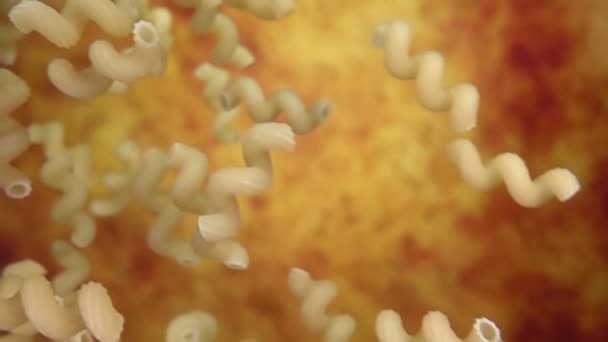 Pasta cellentani fällt diagonal auf einen ockergelben Hintergrund — Stockvideo