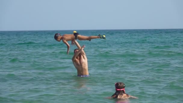 Чоловік кидає маленького хлопчика у воду з бризками — стокове відео