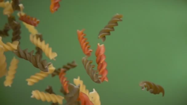 Fusili di pasta secca colorata che volano diagonalmente sullo sfondo verde oliva — Video Stock