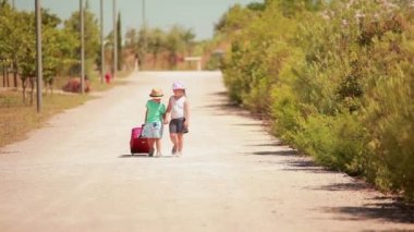 Oğlan ve kız el ele yürüyorlar yol boyunca bir bavulla