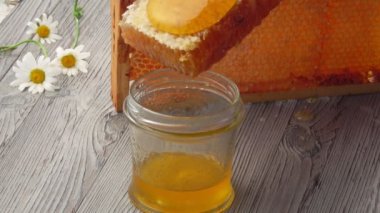 Taze bal, bal peteklerinin yüzeyinden cam kavanoza akıyor.