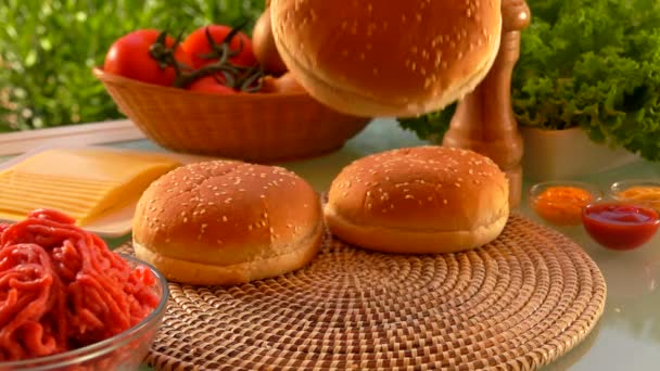 Cesam bun sta cadendo sul tavolo accanto agli ingredienti per cheeseburger — Video Stock