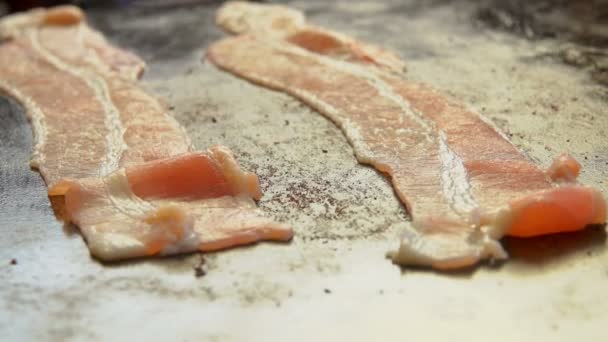 Närbild av remsor av bacon rostning snabbt på den platta grill ytan av grill — Stockvideo