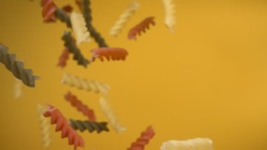 Kuru renkli fusili makarnası sarı arka planda çapraz uçuyor.