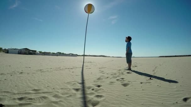 La silueta de un niño mirando la bola del tiempo en la playa — Vídeo de stock