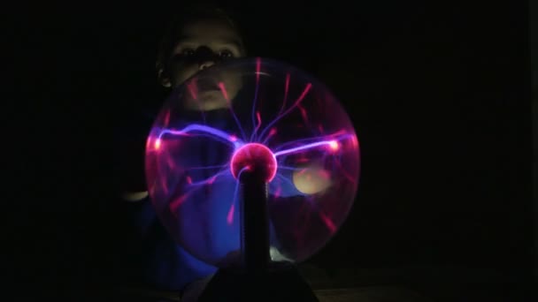 Un petit garçon touche la lampe Tesla avec ses mains
