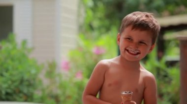 Sevimli neşeli çocuk dışarıda mutlu bir dondurma yiyor. 