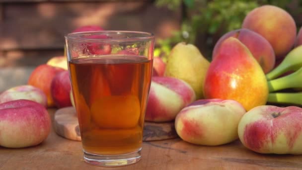 Ett glas fruktjuice på bakgrunden av persikor och bananer utomhus — Stockvideo