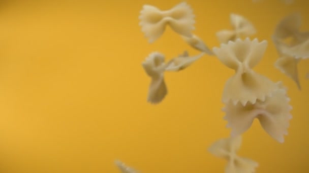 Torr pasta Farfalle flyger diagonalt på en gul bakgrund — Stockvideo