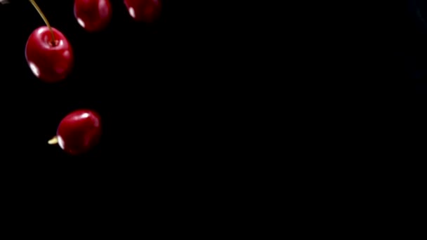 Detailní záběr zralých červených třešní padající diagonálně na černé pozadí — Stock video