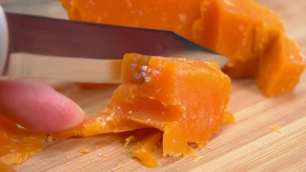 Нож режет и ломает вкусный французский оранжевый сыр Мимолетт — стоковое видео