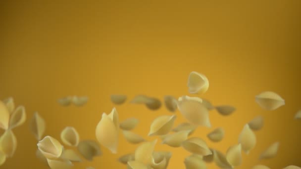 Suché těstoviny Conchiglie rigate letí nahoru a dolů na žlutém pozadí — Stock video