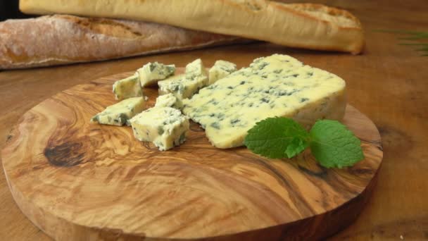 Keju Roquefort biru diletakkan di papan kayu dengan latar belakang baguette Prancis — Stok Video