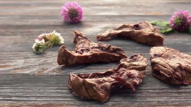 Natuurlijk en gezond hondenvoer op de houten tafel. Gedroogde rundvlees long — Stockvideo