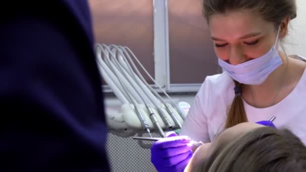 치과의 사는 치과 문제를 이해하기 위해 여성 환자에게 이야기하고 있다 — 비디오