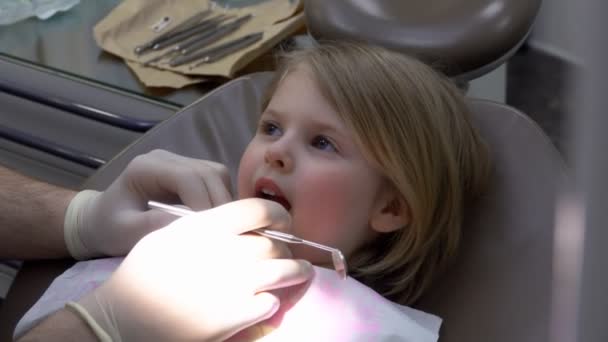 Primer plano del dentista revisando los dientes de una niña linda — Vídeos de Stock