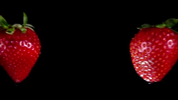 Las fresas grandes vuelan entre sí y chocan sobre fondo negro — Vídeos de Stock