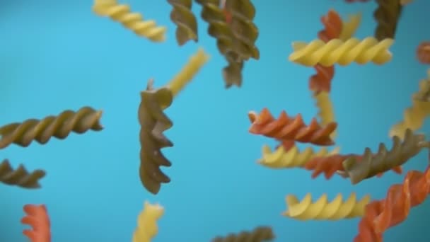 Suché barevné těstoviny fusili létání diagonálně na modrém pozadí oblohy — Stock video
