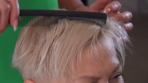 Cabeleireiro está fazendo um corte de cabelo curto para uma mulher loira satisfeita cliente — Vídeo de Stock